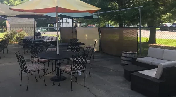 Outdoor patio with wrought-iron tables, colorful umbrellas, and lounge seating.