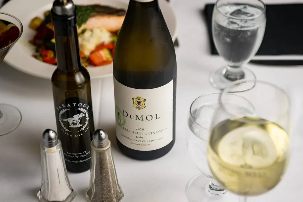 Restaurant table setting with wine, olive oil, shakers, and blurred meal.