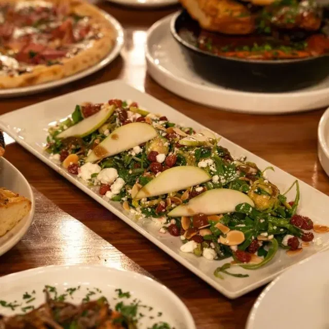 Close-up of vibrant salad with pears, cheese, and berries on wooden table.
