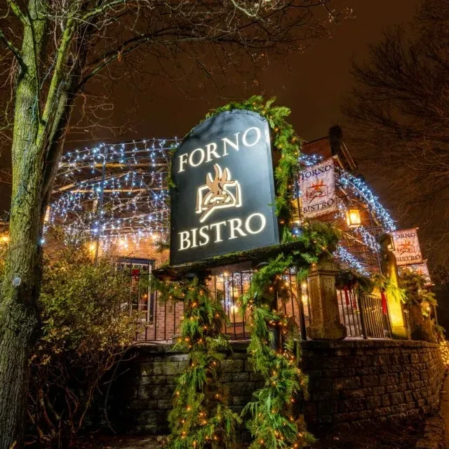 FORNO BISTRO restaurant illuminated with festive string lights at night.