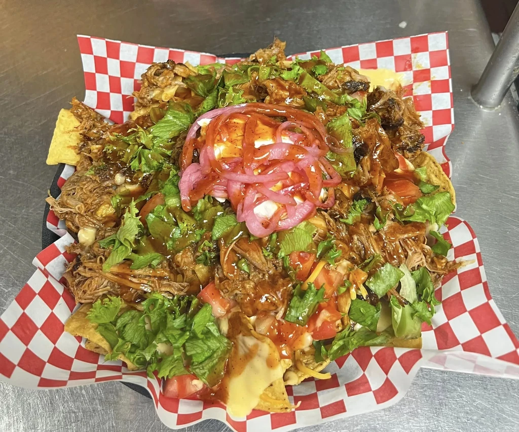 Overhead view: Nachos piled with shredded meat, cheese, and colorful toppings.
