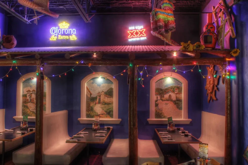 Vibrant Mexican restaurant interior with murals, piñata, string lights, and booths.