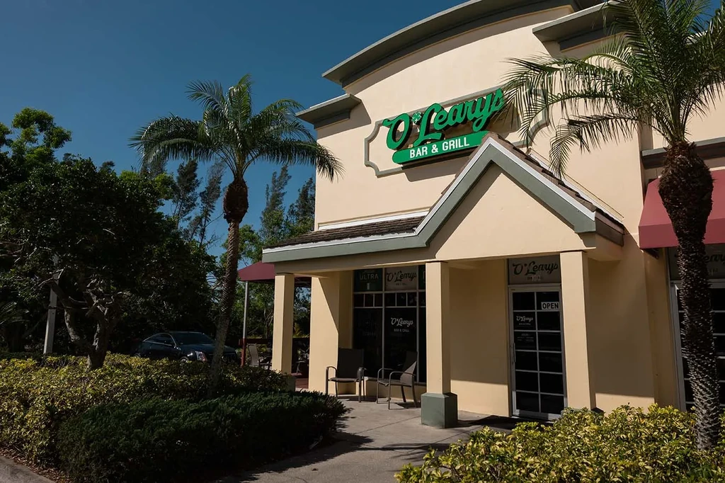 O'Leary's Bar & Grill exterior, green sign, two palm trees.
