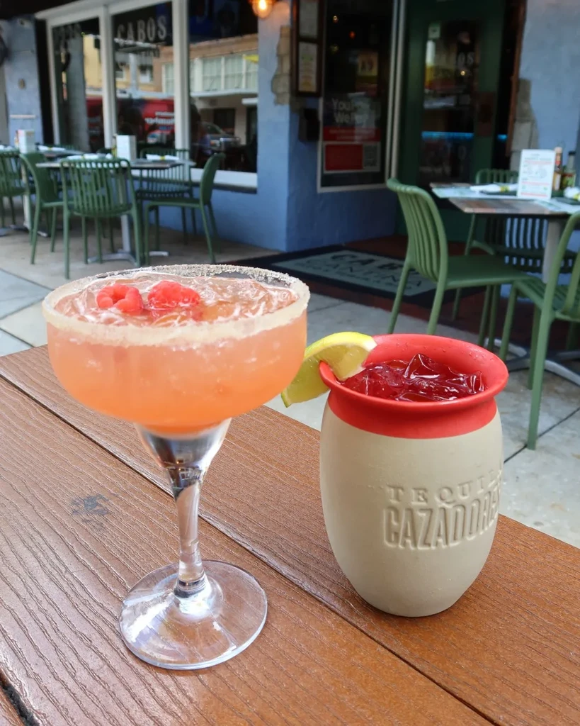 Margarita and red drink in Tequila Cazadores mug on patio table.