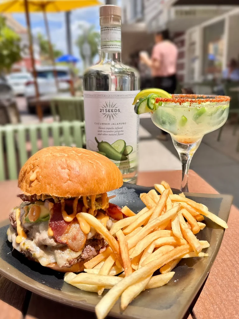 Burger, fries, 21 Seeds tequila, and cocktail on outdoor patio.