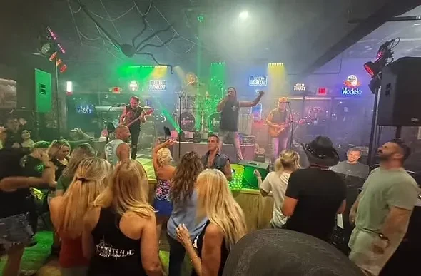 Live band performs on colorful stage for a dancing crowd.