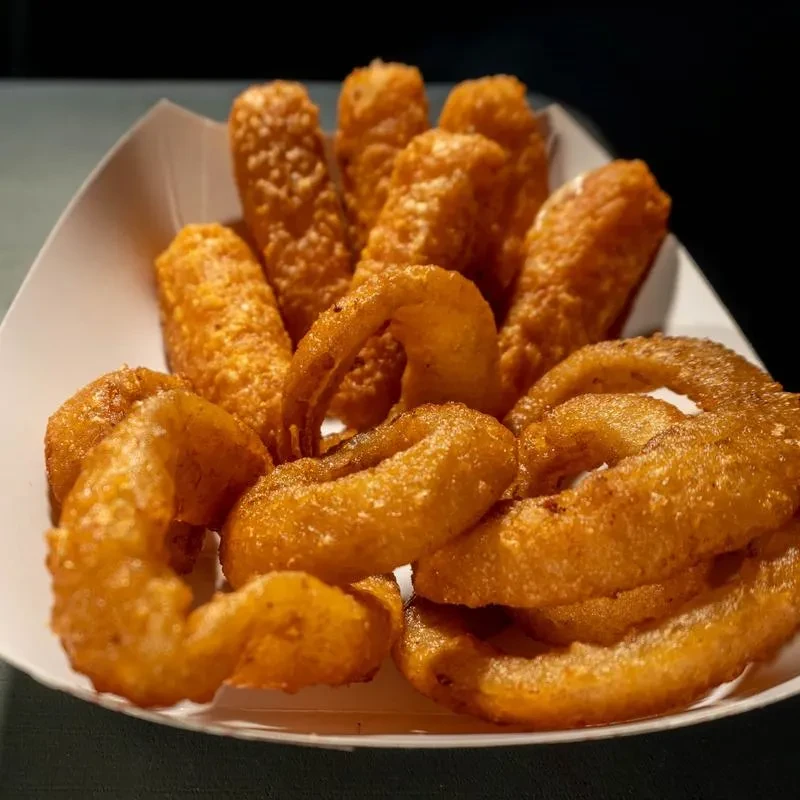 Crispy fried onion rings and breaded sticks in a white tray.
