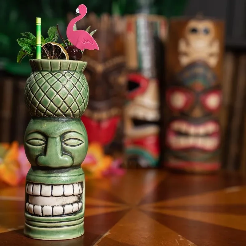Green totem mug tiki cocktail with flamingo, mint, and citrus garnish.
