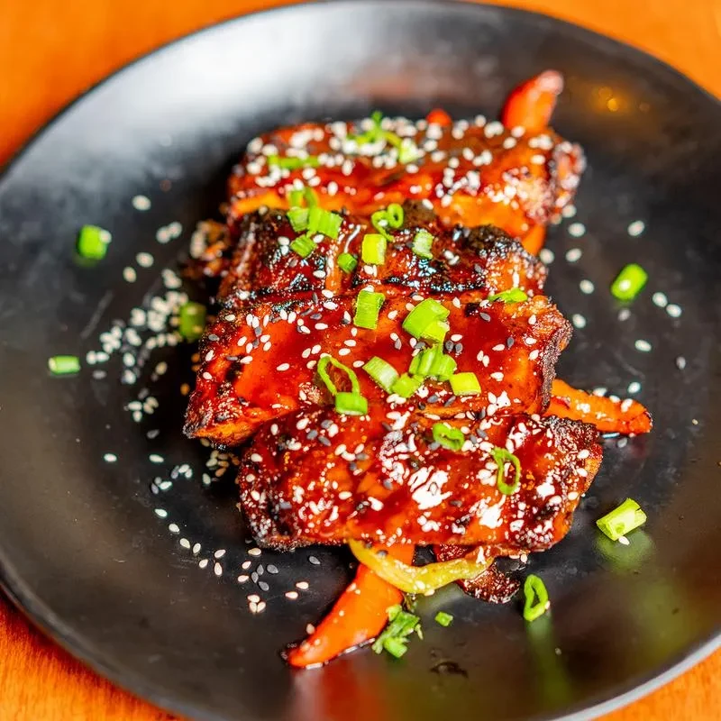 Glossy glazed meat topped with sesame and green onions.