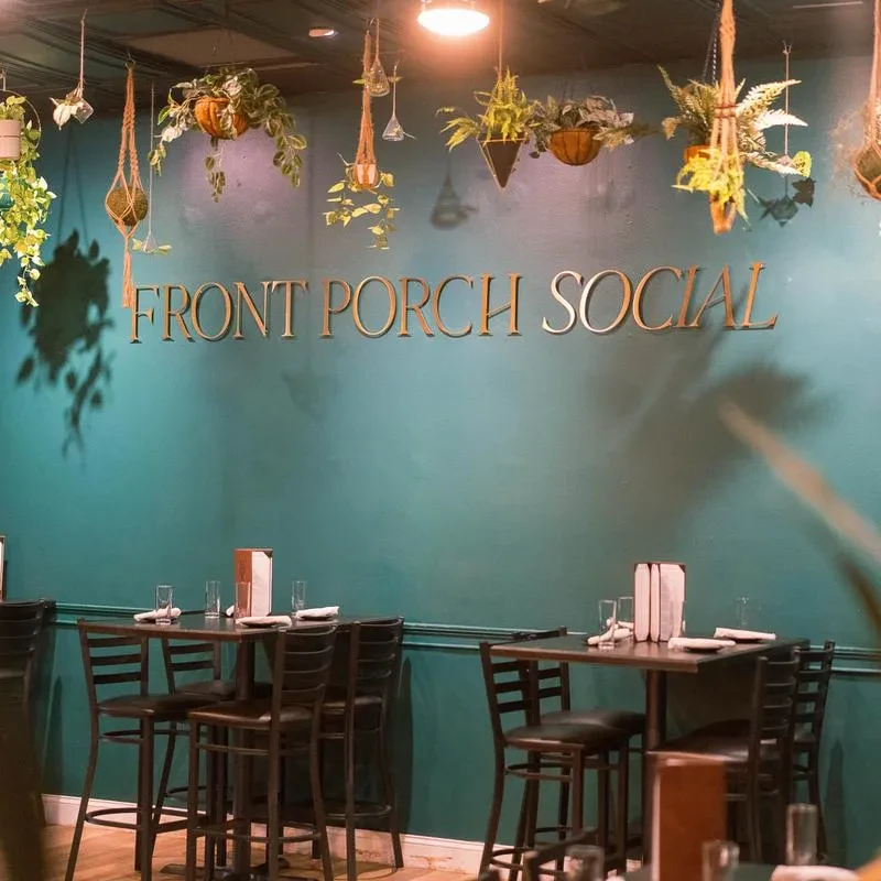 Teal accent wall with gold 'FRONT PORCH SOCIAL' sign, hanging plants.