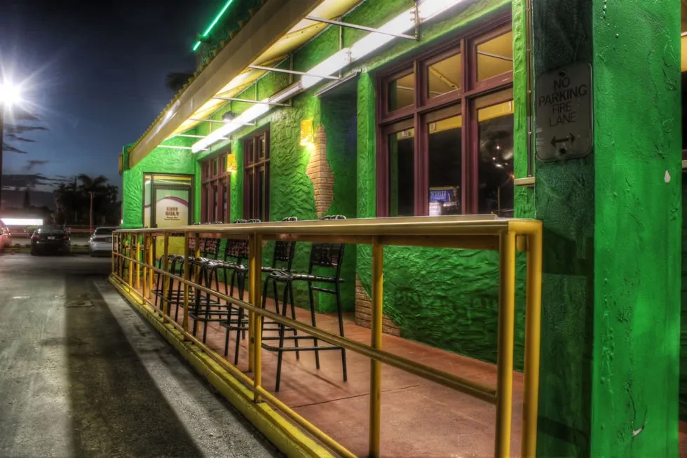 Lime green building exterior, yellow bar, brightly lit at night.