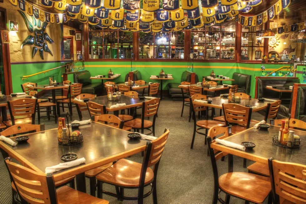 Vibrant, empty Mexican restaurant interior with lime green walls and Corona banners.