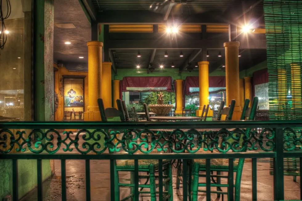 Vibrant, empty restaurant patio at night with yellow pillars and fountain.