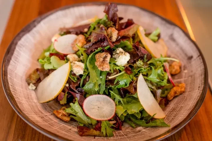 Salad with mixed greens, pear, radish, cheese, nuts, and berries.