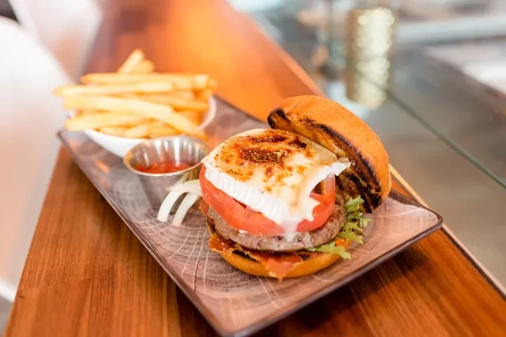 Gourmet burger with melted cheese, golden fries, and ketchup.