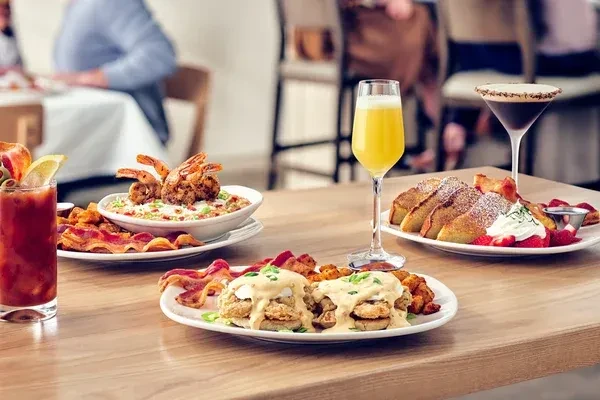 Restaurant table with biscuits, shrimp and grits, French toast, and beverages.