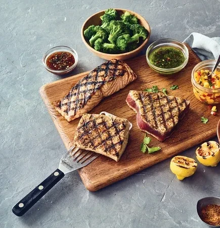 Overhead shot of grilled salmon, seared tuna, broccoli, sauces, and lemon.