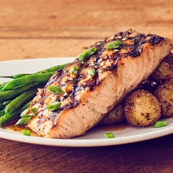 Grilled salmon, roasted potatoes, and green beans on a white plate.