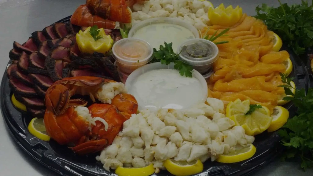Black catering platter with crab, smoked salmon, seared tuna, lobster, sauces.