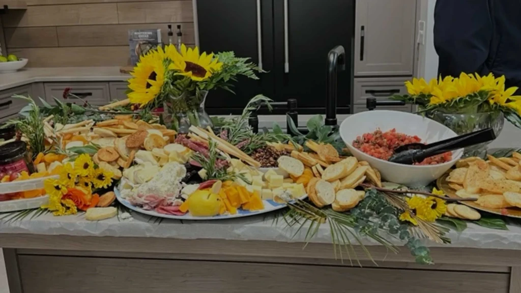 Lavish charcuterie board with cheeses, meats, and sunflowers on kitchen island.