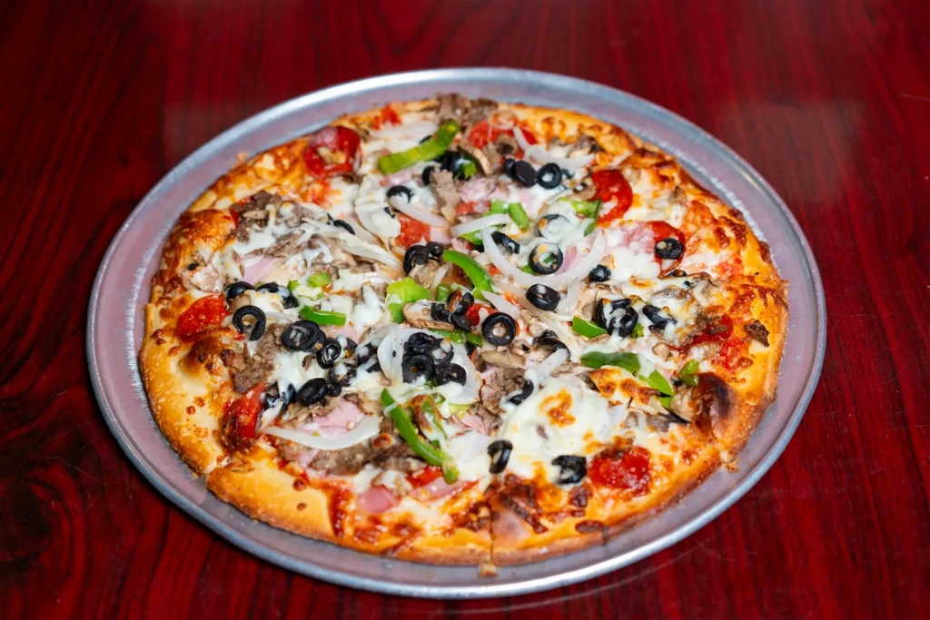 Large, whole pizza with diverse toppings on a silver pan.