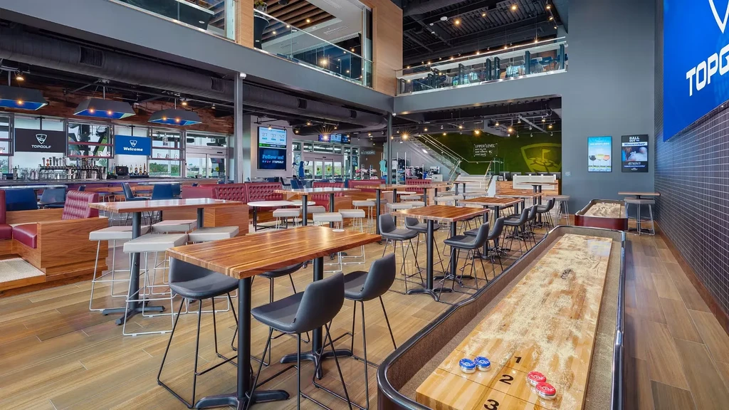 Topgolf venue with dining, bar, shuffleboard, and multi-level golf bays.