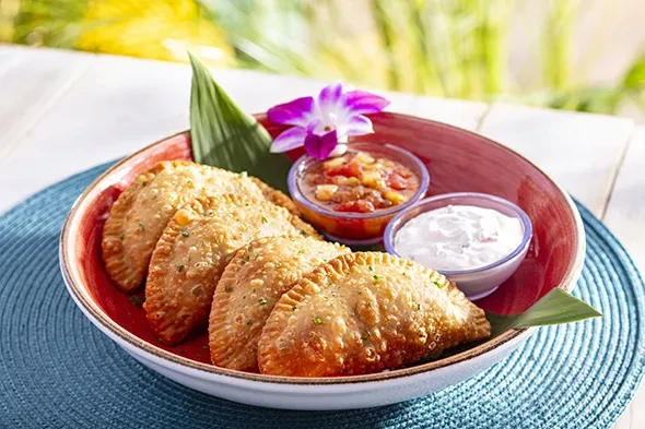 Five crispy fried pastries with herbs, red salsa, and white dip.