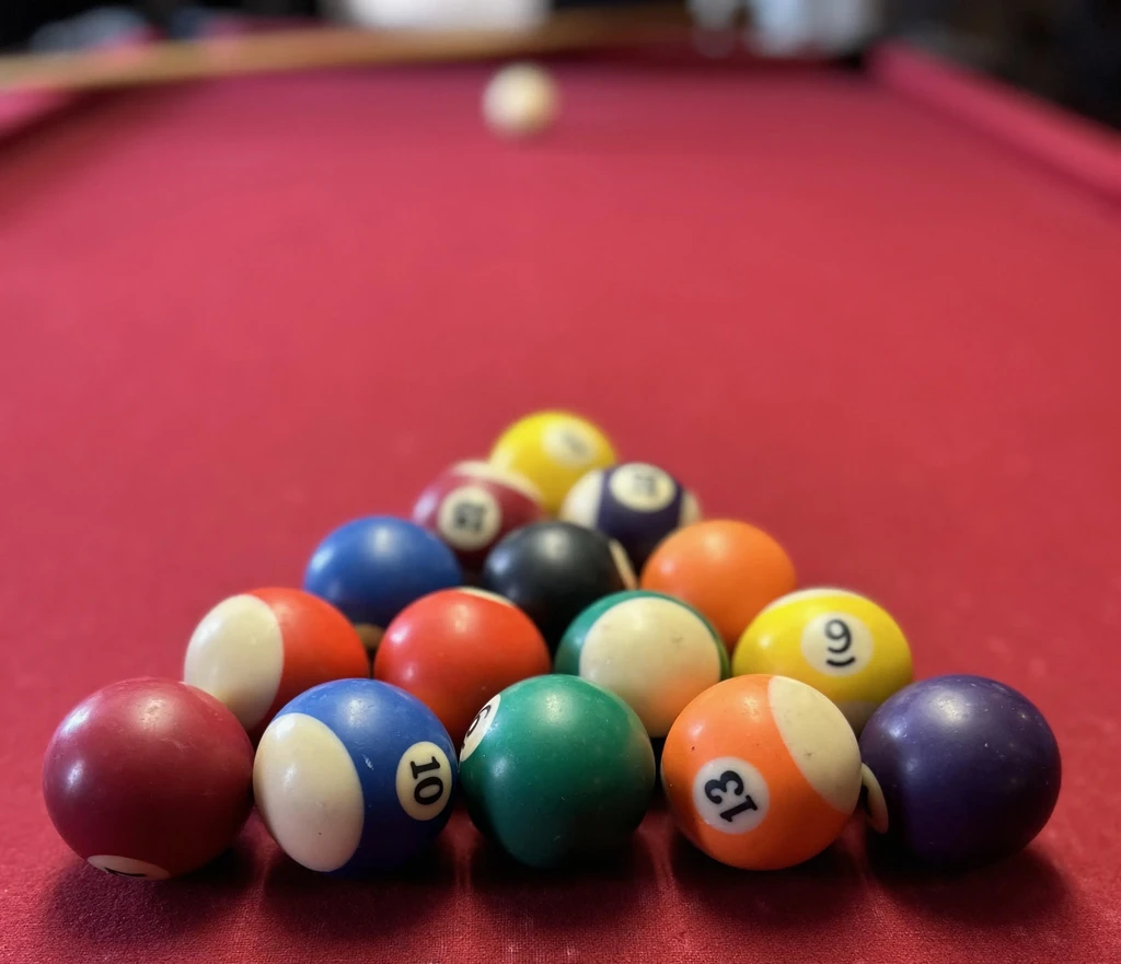 Colorful billiard balls racked on a vibrant red felt pool table.