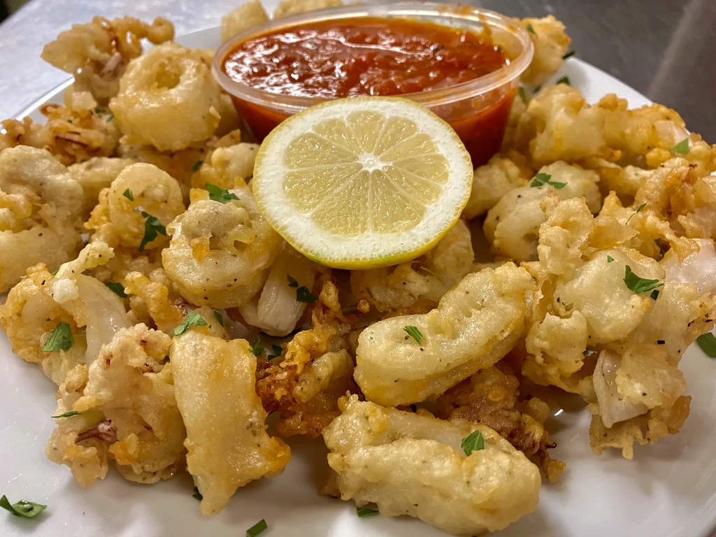 Crispy fried calamari, lemon slice, parsley, and red dipping sauce.