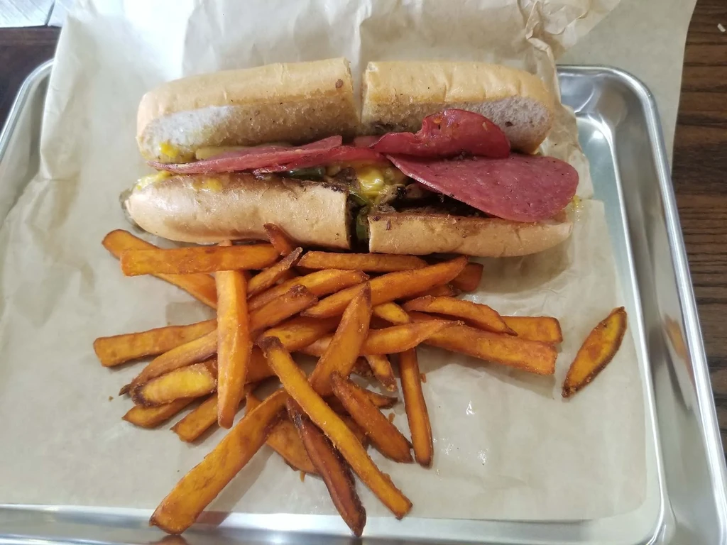 Hoagie sandwich halves with meat, cheese, and sweet potato fries.
