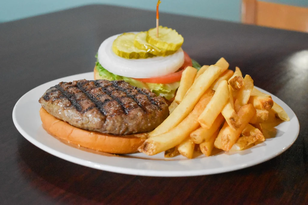 Plate with a grilled burger, stacked vegetables, and golden french fries.