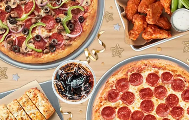 Vibrant fast food spread with pizzas, wings, breadsticks, and soda.