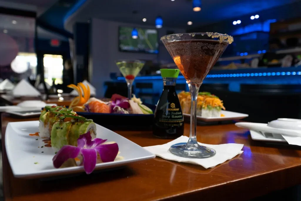 Sushi rolls, sashimi, and drinks on a table at a modern sushi bar.