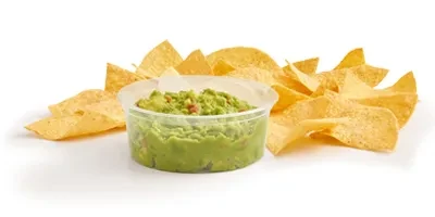 Guacamole in a transparent container surrounded by golden tortilla chips.