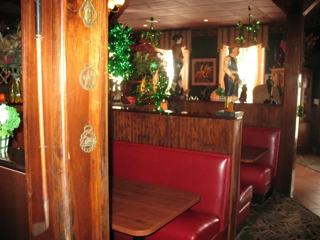Traditional restaurant interior with red booths, dark wood, golf club, and statues.
