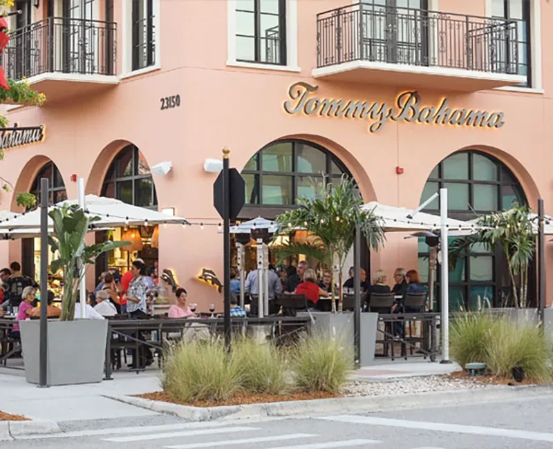 Peach Tommy Bahama restaurant, arched windows, lively outdoor dining patio.