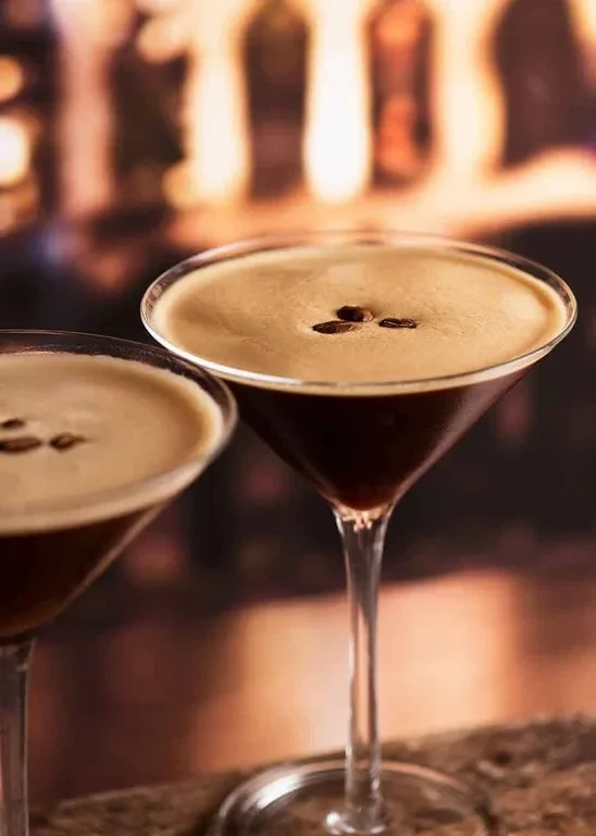 Two martini glasses with foamy coffee drinks and coffee bean garnish.