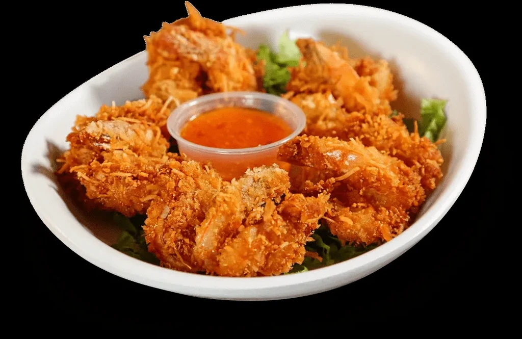 Crispy coconut shrimp with dipping sauce and lettuce in a white bowl.
