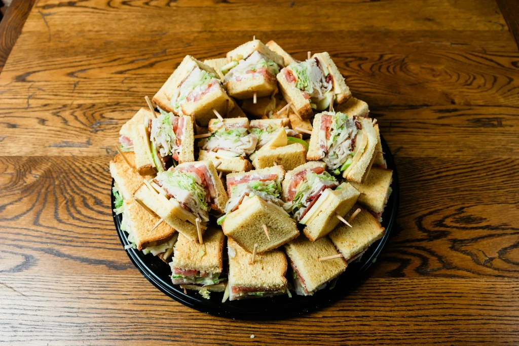 Platter of quartered club sandwiches with bacon, lettuce, and tomato.