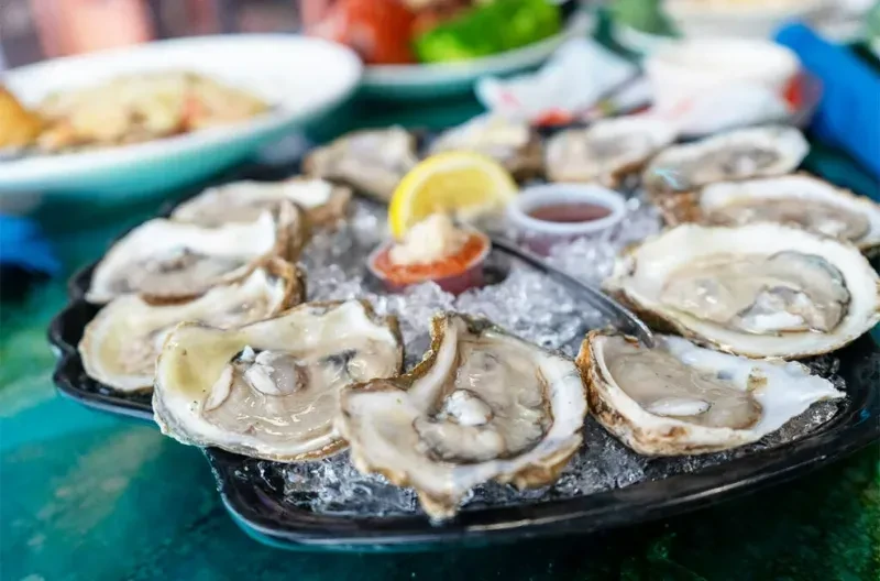 Fresh shucked oysters on ice, with lemon and condiments.