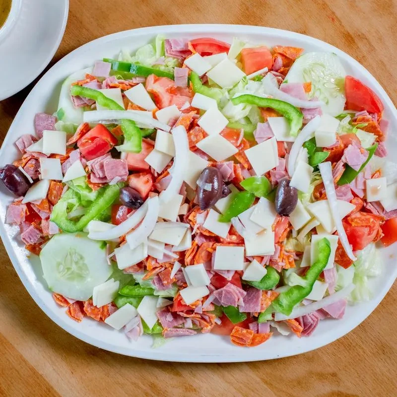 Large colorful mixed salad with ham, pepperoni, cheese, vegetables, olives.