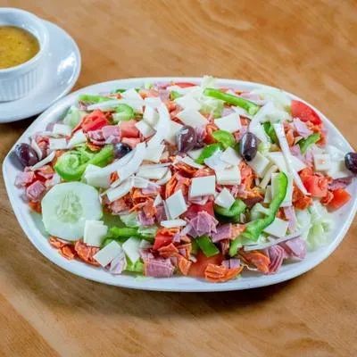 Vibrant mixed salad with lettuce, tomatoes, cheese, deli meats, and olives.