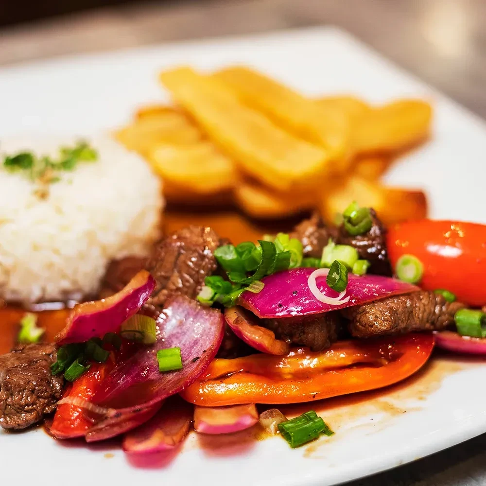 Stir-fry with beef, vegetables, rice, and fries on a white plate.