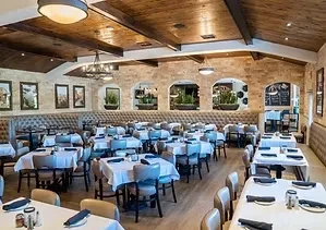 Elegant, empty restaurant with vaulted wooden ceiling and set tables.