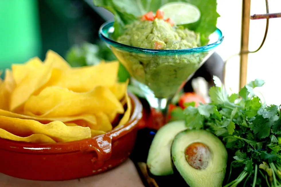Fresh guacamole and tortilla chips with avocado and cilantro.