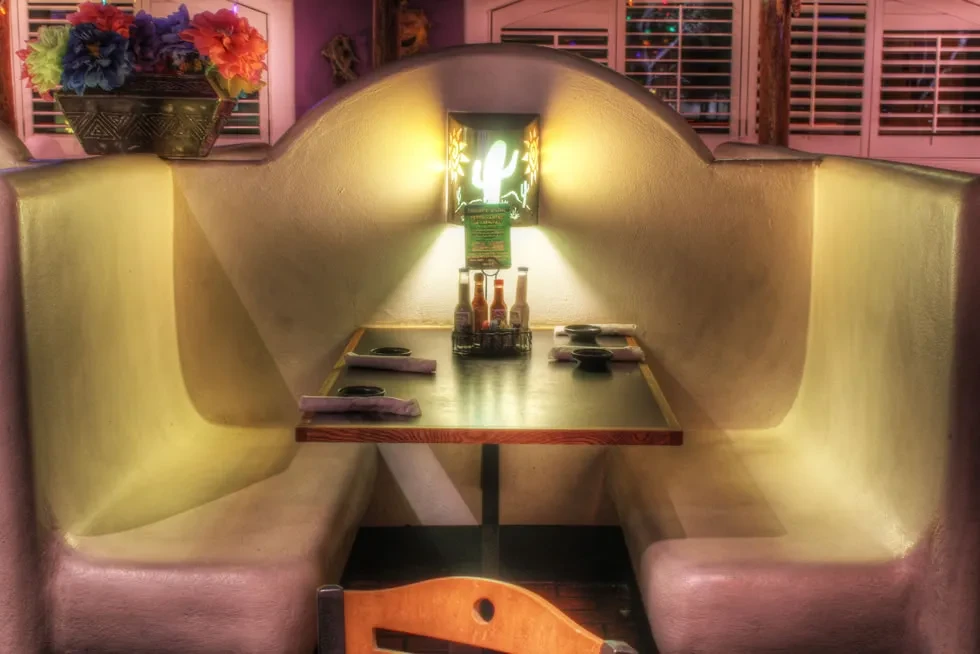 Southwestern restaurant booth with adobe walls and a green cactus neon sign.