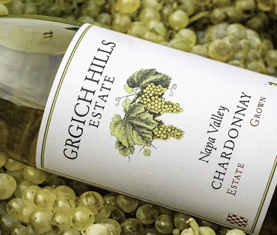 Grgich Hills Estate Chardonnay label and bottle, surrounded by grapes.