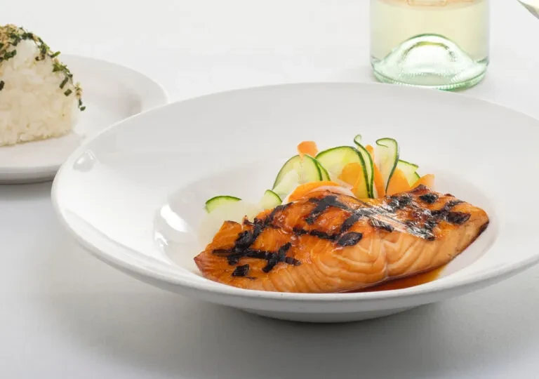Grilled salmon fillet with grill marks, cucumber, and carrots.