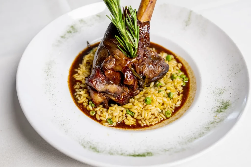 Braised meat shank on orzo with green peas, rosemary, and dark gravy.