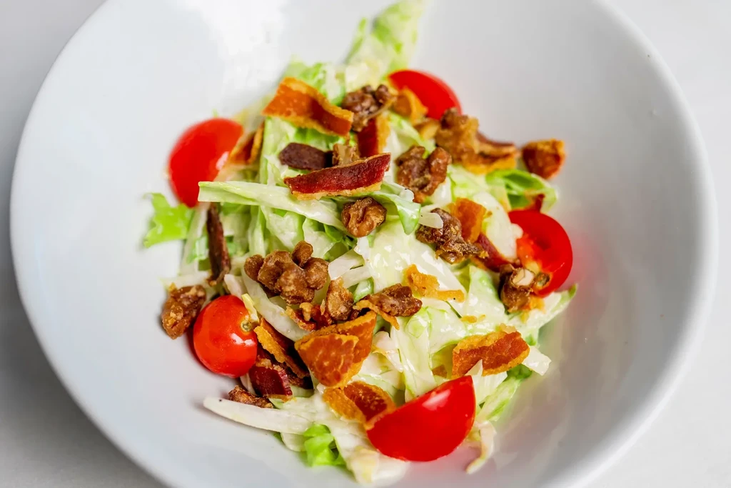 Fresh salad with lettuce, tomatoes, bacon bits, pecans, creamy dressing.